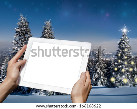 Tablet in the hands and tree with lights on background