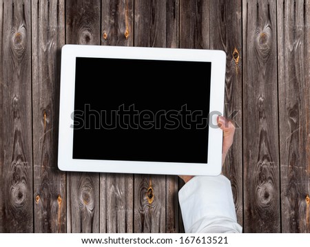 tablet in the hands of women on the background of an old table with boards