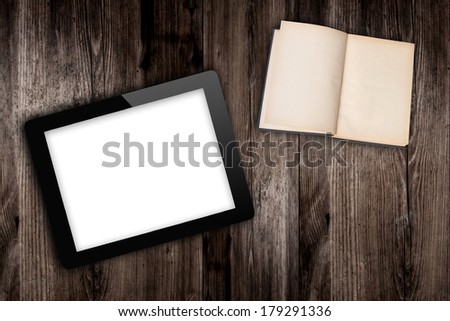 tablet computer and book  on old wooden table
