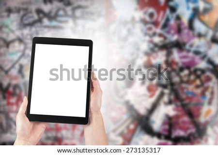 tablet in the hands of women and graffiti in the background