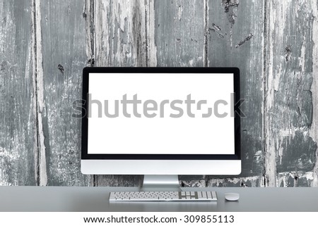 desktop computer on a table and a wall of wooden planks in the background
