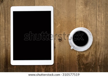 Tablet pc looking like ipad on table with coffee cup