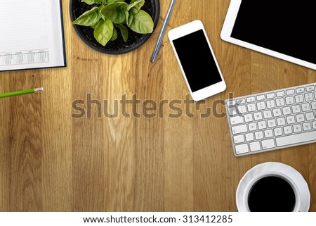 Office table with tablet, computer, coffee cup and flower. View from above with copy space