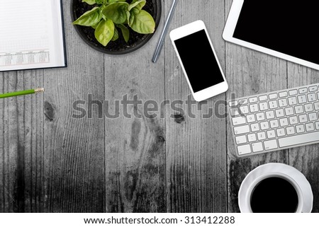 Office table with tablet, computer, coffee cup and flower. View from above with copy space