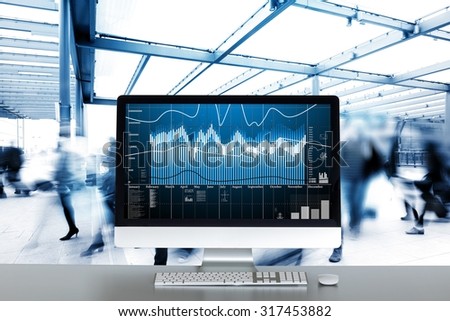 desktop computer on a table with statistics on screen and background rush in the office