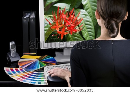 Designer at work. Color samples on table. Vivid picture on computer monitor.