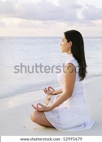 Young woman practicing yoga at sunrise near the ocean