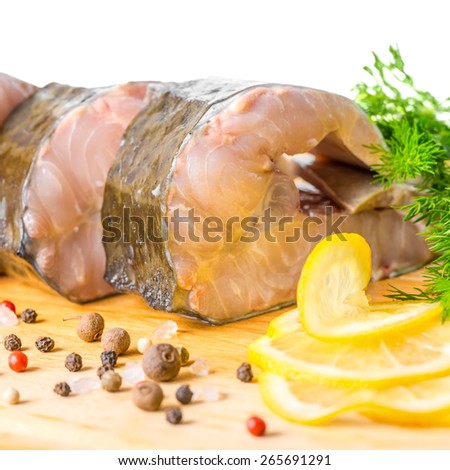 raw fillet steak of sturgeon fish with greens, lemon, different peppers and salt, isolated on white background, closeup