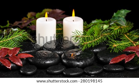 winter spa concept of zen basalt stones, evergreen branches, red leaves with drops and candles, closeup