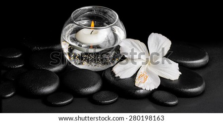 beautiful spa concept of dew white hibiscus flower and candles in vase with water on zen stones, panorama