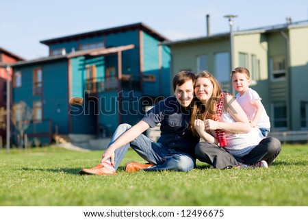 Happy young family of three having fun in front of theirs house at sunny day.
