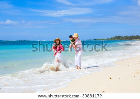 Family vacation. Young family of four on white sand tropical beach