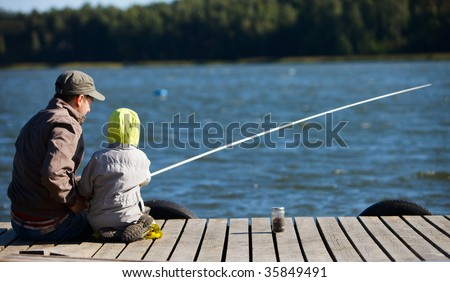 Father and small son fishing together on lake