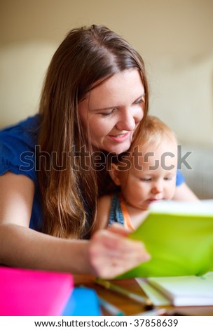 Young mother and her baby daughter reading together. Can be used also in kindergarten/daycare context.