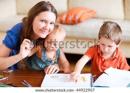 Young mother and her two kids drawing together. Can be used also in kindergarten/daycare context