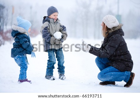 Mother and two kids having fun outdoors on beautiful winter day