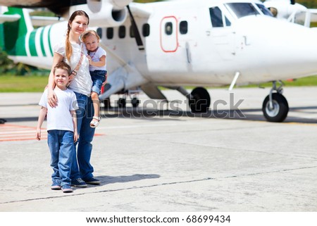 Young mother with her two kids standing in front of small airplane
