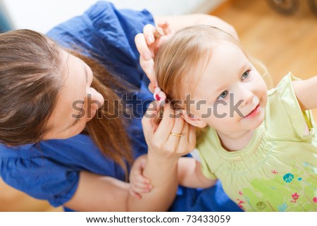 Portrait of young woman brushing her daughter\'s hair