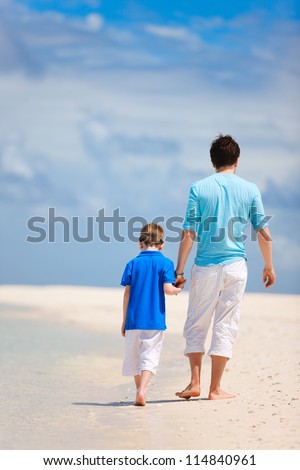 Back view of father and son walking on a tropical beach
