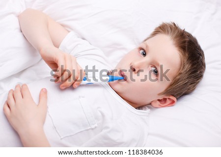 Portrait of sick little boy measuring body temperature