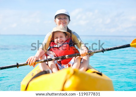 Mother and son kayaking at tropical ocean