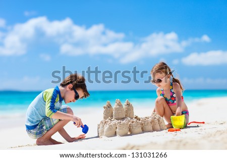 Brother and sister making sand castle at tropical beach