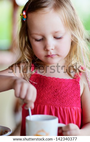 Adorable little girl in restaurant drinking hot chocolate