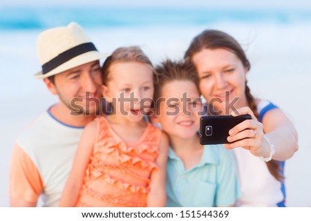 Beautiful family at beach making a self portrait with mobile phone