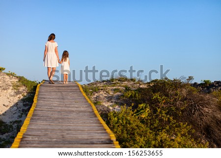 Back view of mother and daughter walking along a wooden path