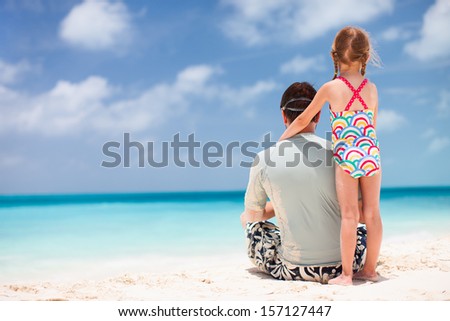 Back view of father and daughter enjoying beach vacation