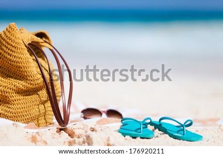 Straw bag, sun glasses, towel and flip flops on a tropical beach