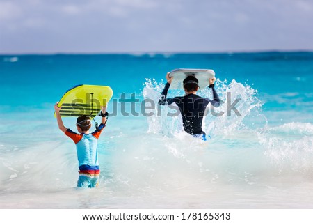 Father and son running towards ocean with boogie boards
