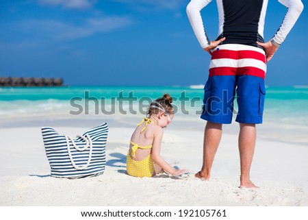 Back view of father and daughter at tropical beach