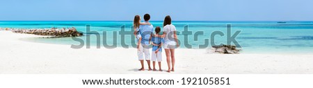 Back view of a beautiful family on a beach during summer vacation. Wide panorama, perfect for banners