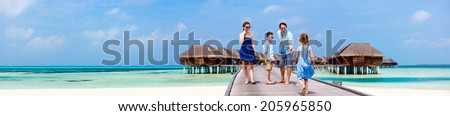 Happy beautiful family walking on wooden jetty during summer vacation at luxury resort wide panorama with copy space, perfect for banners