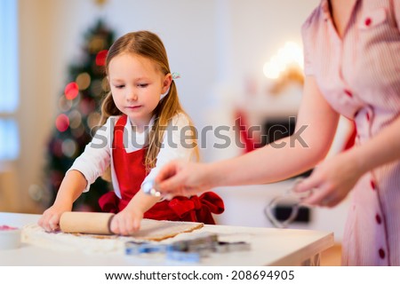 Family of mother and daughter baking gingerbread Christmas cookies at cozy home on winter day