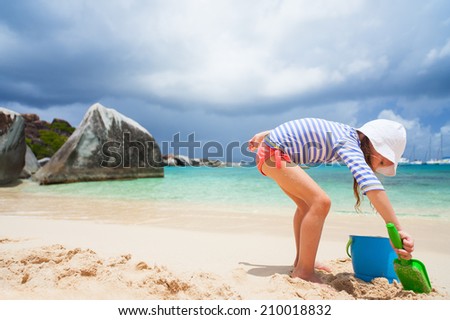 Adorable little girl wearing sun protection rash guard at beach during summer vacation