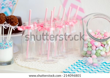 Candy jar and fancy milk bottles for drinks on a dessert table at party or wedding celebration