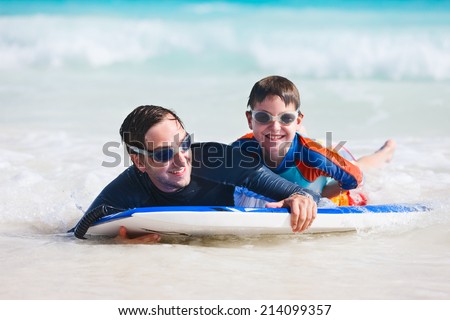 Father and son on vacation having fun surfing on boogie board