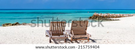 Panorama of a wooden lounge chairs on a beautiful tropical beach at Maldives