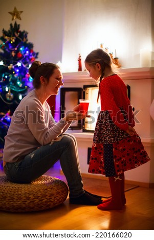Mother and daughter sitting by a fireplace in their family home on Christmas eve