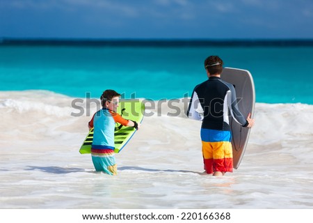 Father and son running towards ocean with boogie boards having fun on beach vacation