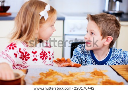 Kids wearing warm sweaters baking cookies in house kitchen on winter day