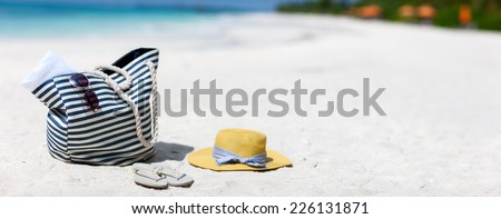 Straw hat, bag, sun glasses and flip flops on a tropical beach