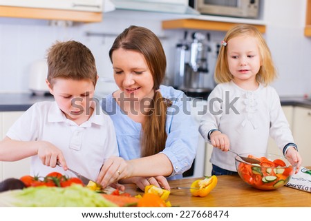 Young mother and her two kids making vegetable salad