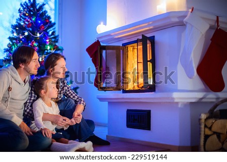 Family sitting by a fireplace in their home on Christmas eve