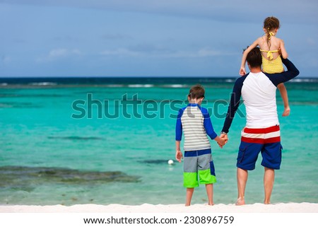 Back view of father and kids at tropical beach during summer vacation