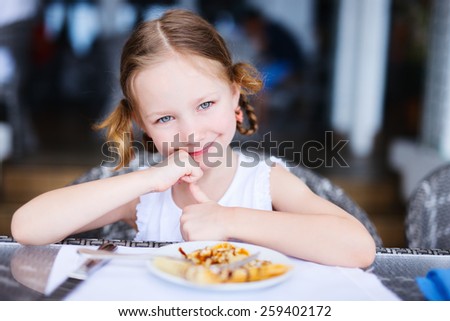 Adorable little girl eating breakfast in restaurant