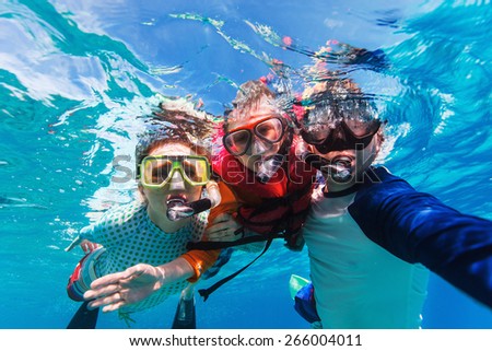 Underwater portrait of family snorkeling together at clear tropical ocean