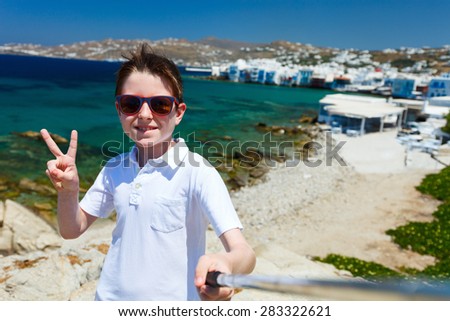 Cute teenage tourist making selfie with a stick at place overlooking Little Venice area on Mykonos island, Greece